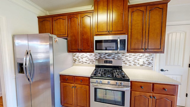 kitchen featuring stainless steel appliances, light countertops, crown molding, and tasteful backsplash