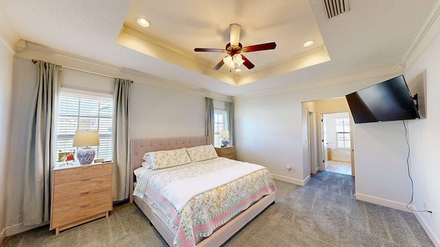 bedroom with baseboards, visible vents, light colored carpet, ornamental molding, and a tray ceiling