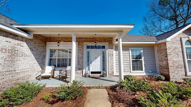 entrance to property with covered porch and brick siding