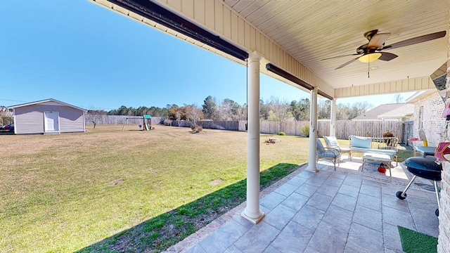 view of patio / terrace with an outbuilding, a playground, a fenced backyard, a ceiling fan, and a storage unit