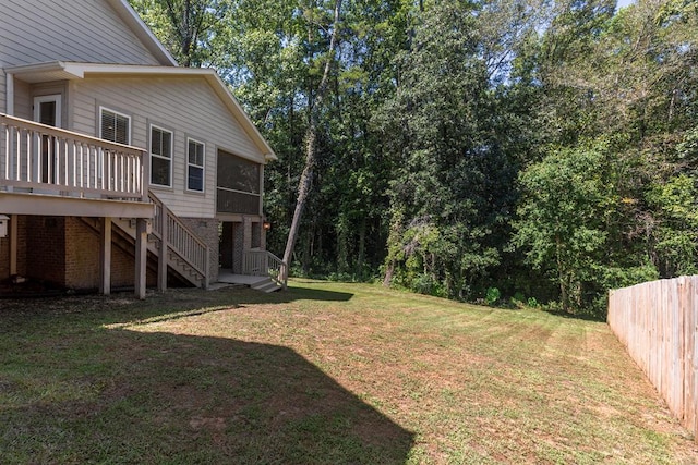 view of yard featuring a deck, stairway, fence, and a sunroom