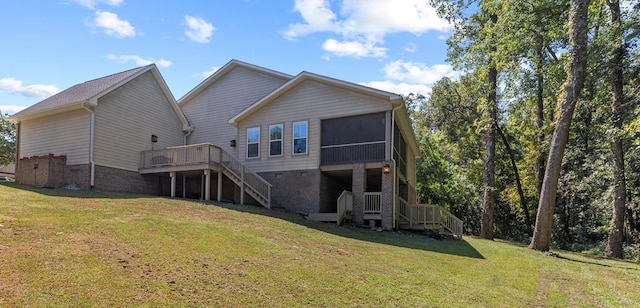 back of property featuring a deck, stairway, a lawn, and a sunroom