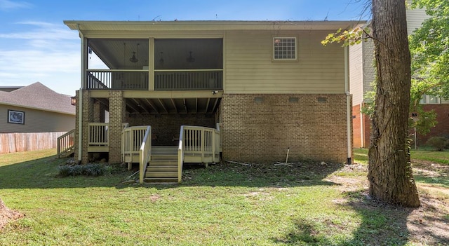 rear view of house with a yard, brick siding, a wooden deck, and a sunroom