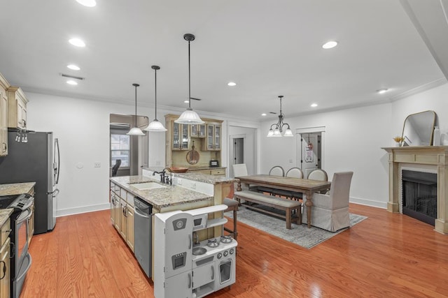 kitchen featuring a sink, light wood-style floors, appliances with stainless steel finishes, an island with sink, and glass insert cabinets