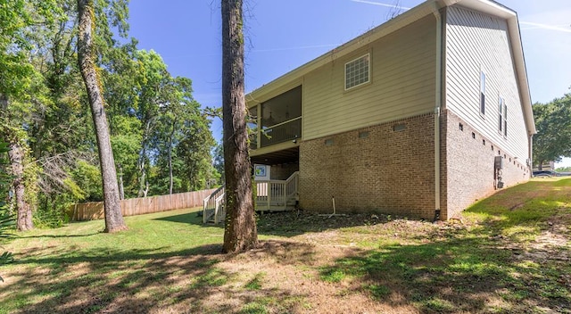 exterior space featuring brick siding, fence, a balcony, and a lawn