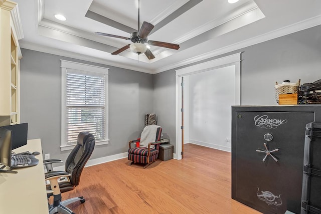 office space featuring a tray ceiling, crown molding, light wood-style flooring, and ceiling fan