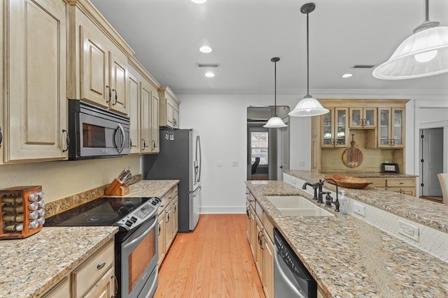 kitchen with a sink, visible vents, appliances with stainless steel finishes, light wood finished floors, and glass insert cabinets