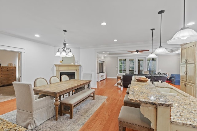 dining space featuring french doors, a fireplace, recessed lighting, ornamental molding, and light wood-type flooring