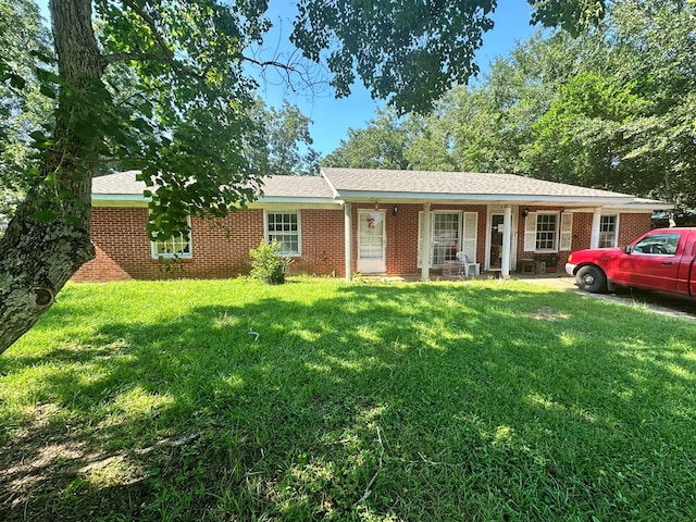 ranch-style home featuring covered porch and a front yard