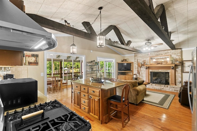 668 Lake Front Dr, Abbeville, AL 36310 - kitchen featuring range hood, ceiling fan, a fireplace, light wood finished floors, and beamed ceiling