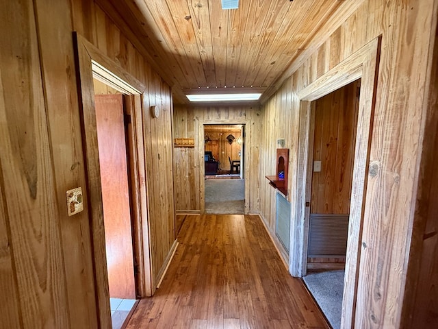 corridor featuring wood walls, wooden ceiling, and wood finished floors