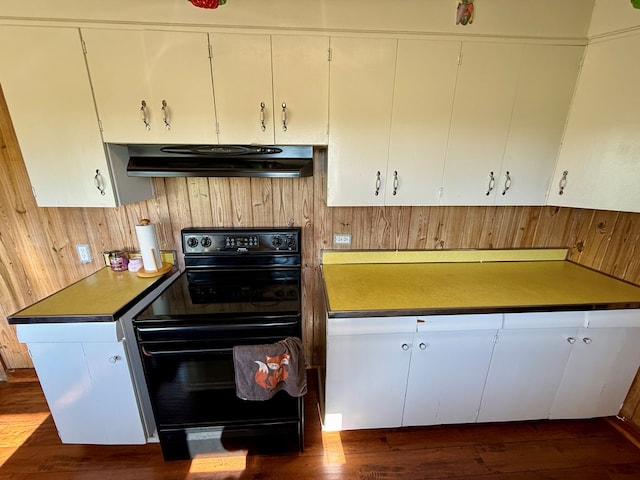 kitchen featuring white cabinets, dark wood-style flooring, under cabinet range hood, wood walls, and black electric range