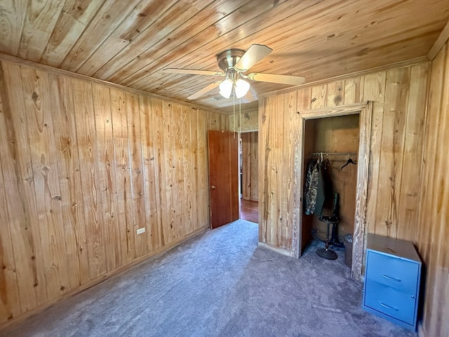 unfurnished bedroom with wood ceiling, wooden walls, a closet, and carpet floors