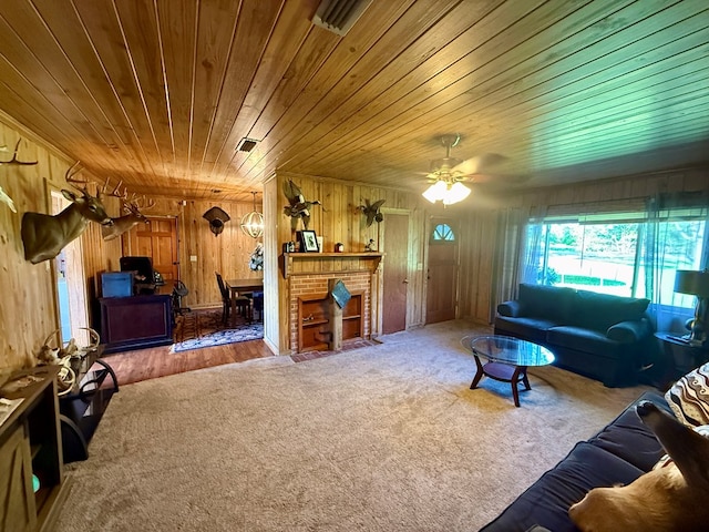 living area featuring wooden walls, wooden ceiling, a ceiling fan, and carpet floors