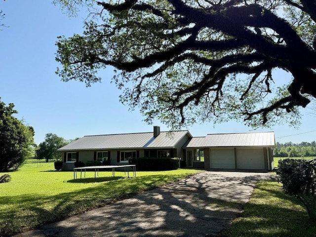 ranch-style home featuring a garage, a front yard, metal roof, and driveway