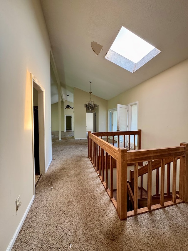 corridor with a notable chandelier, lofted ceiling with skylight, and carpet floors