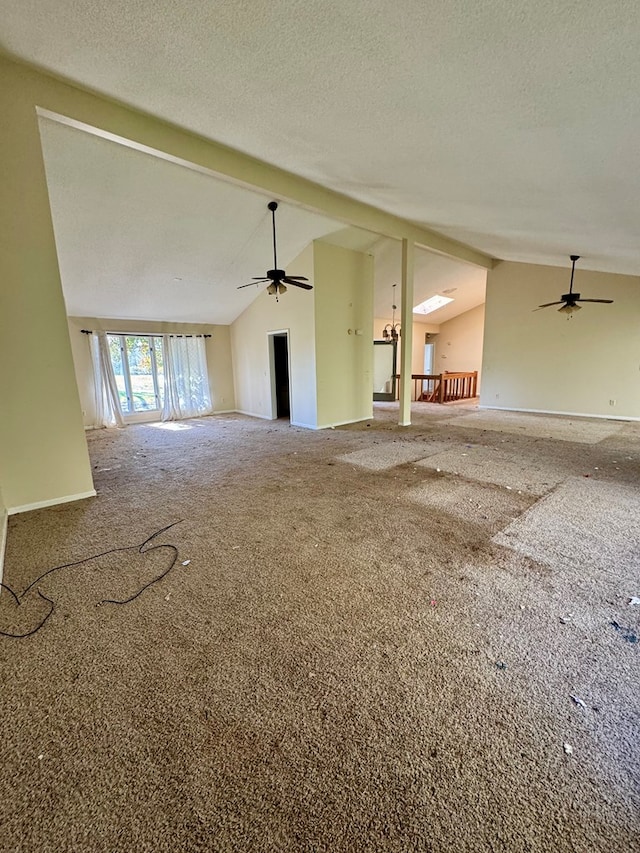 unfurnished living room featuring carpet, a textured ceiling, vaulted ceiling with beams, and ceiling fan