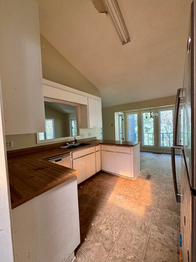 kitchen with sink, kitchen peninsula, a textured ceiling, and vaulted ceiling