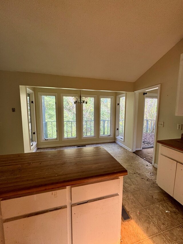 kitchen with a healthy amount of sunlight, butcher block counters, lofted ceiling, and a textured ceiling