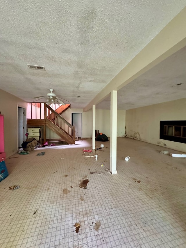 unfurnished living room with ceiling fan and a textured ceiling