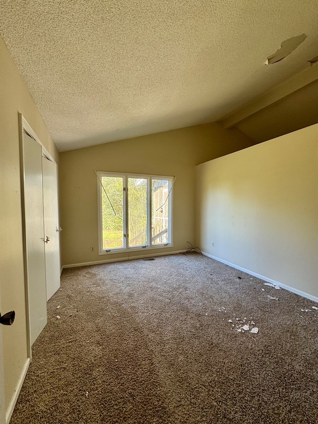 carpeted spare room featuring lofted ceiling with beams and a textured ceiling