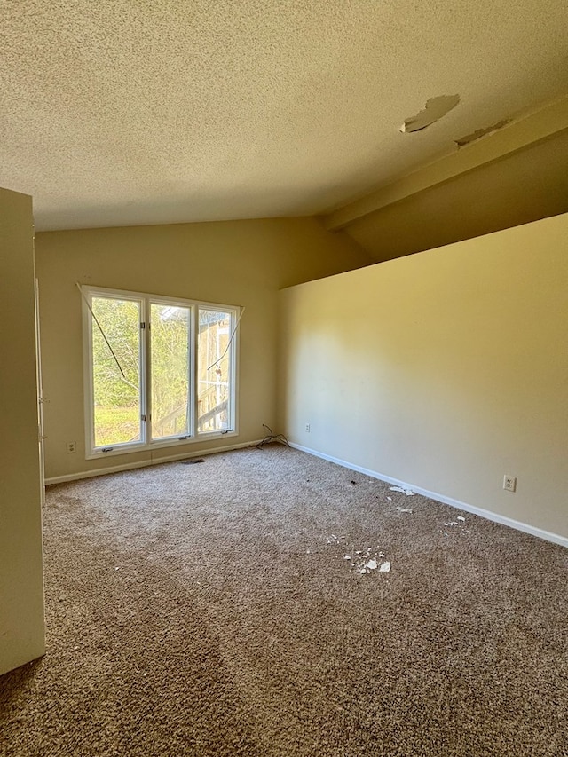 spare room featuring carpet flooring, lofted ceiling with beams, and a textured ceiling