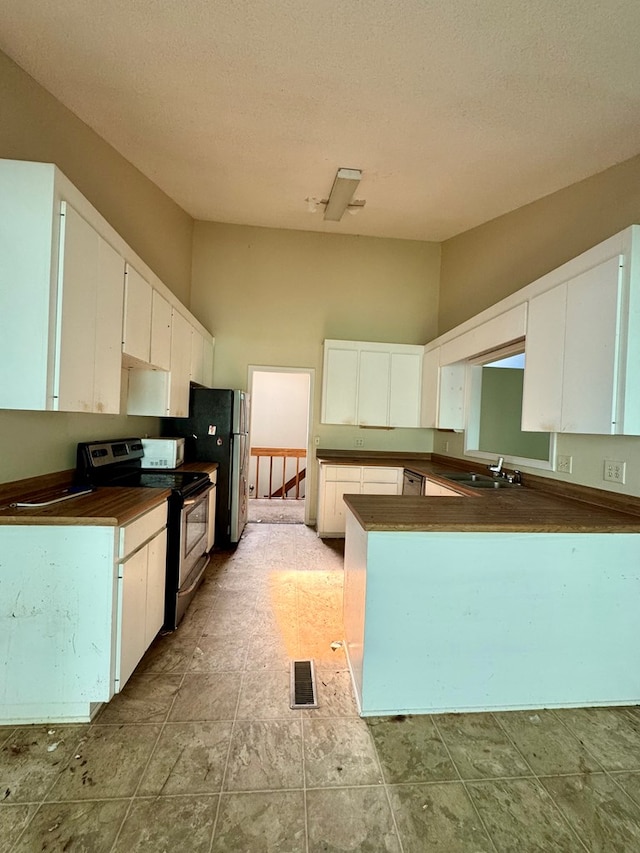 kitchen featuring kitchen peninsula, range with electric stovetop, white cabinetry, and a textured ceiling