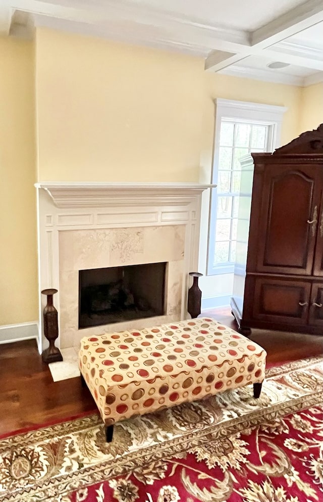 living area with a premium fireplace, coffered ceiling, wood finished floors, baseboards, and beam ceiling