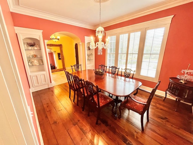 dining area featuring arched walkways, crown molding, a notable chandelier, wood-type flooring, and baseboards