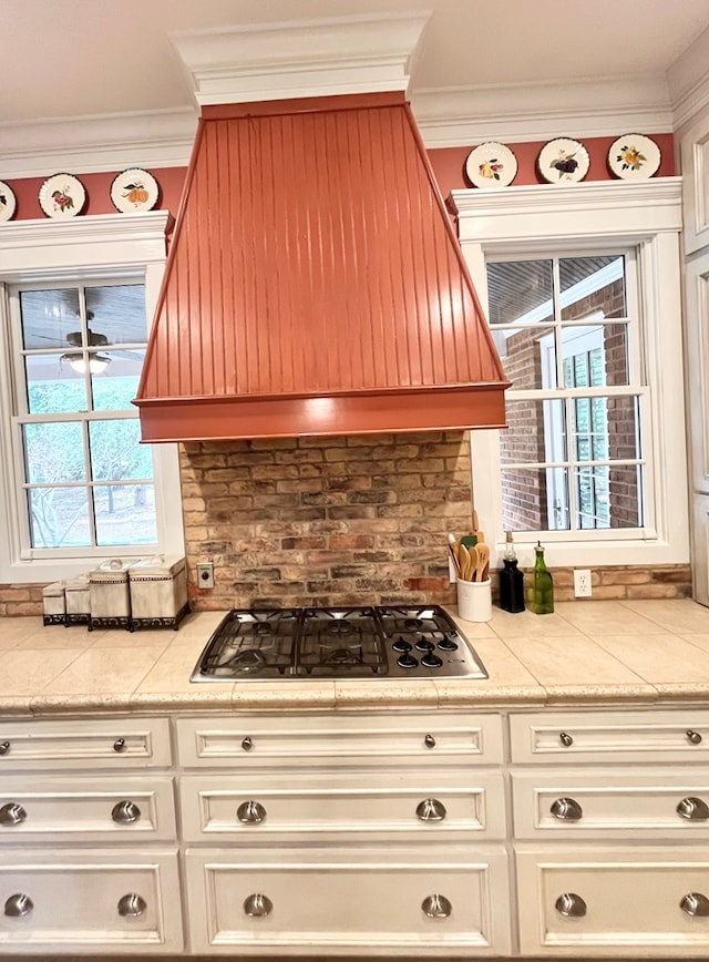 kitchen featuring crown molding, light countertops, premium range hood, and stainless steel gas stovetop