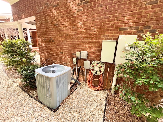 details featuring decorative columns, electric meter, cooling unit, and brick siding