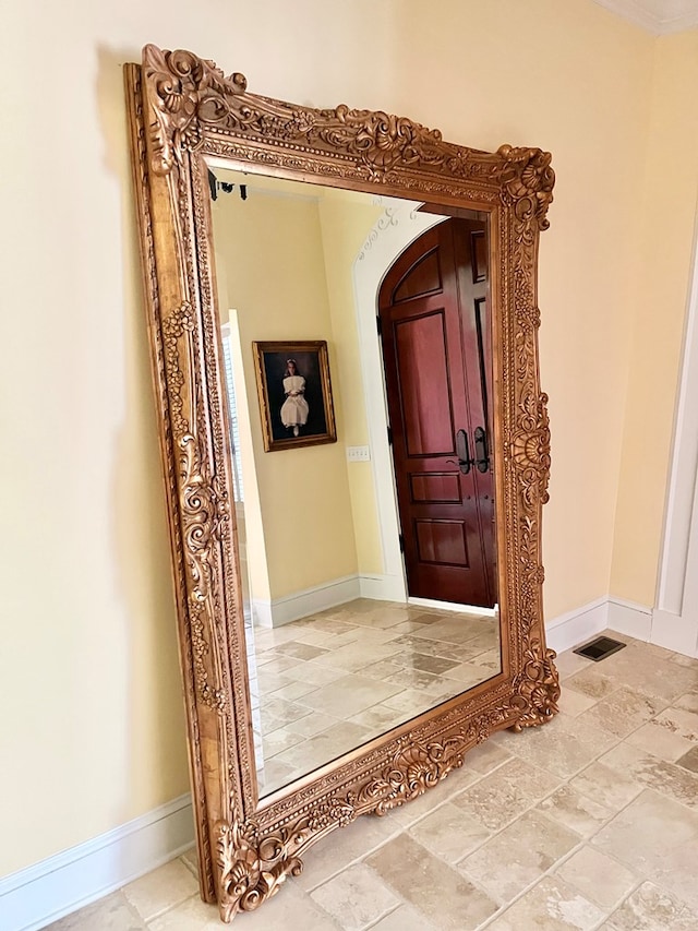 foyer entrance featuring stone finish floor, visible vents, and baseboards