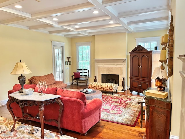 sitting room with light wood finished floors, coffered ceiling, beam ceiling, and a high end fireplace