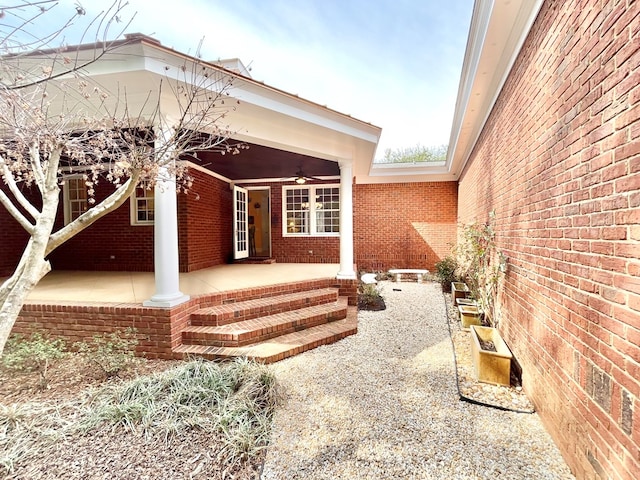 property entrance with brick siding and ceiling fan