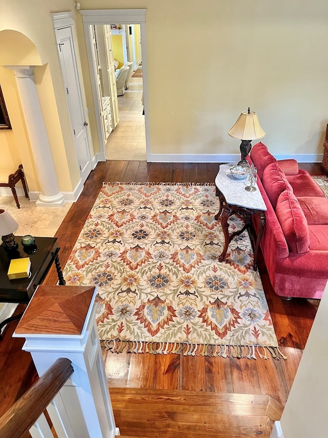 living room with baseboards, arched walkways, and hardwood / wood-style floors