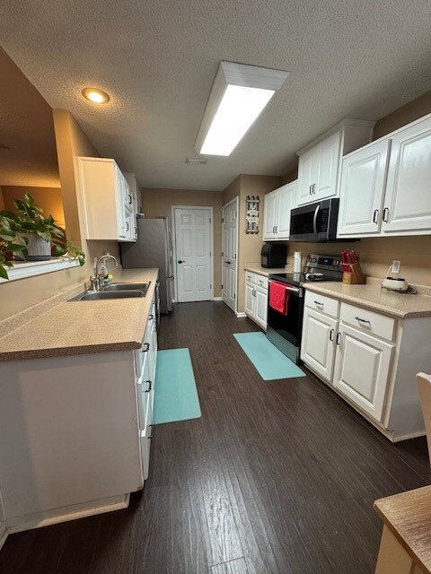 kitchen featuring dark hardwood / wood-style flooring, white cabinetry, a textured ceiling, and appliances with stainless steel finishes