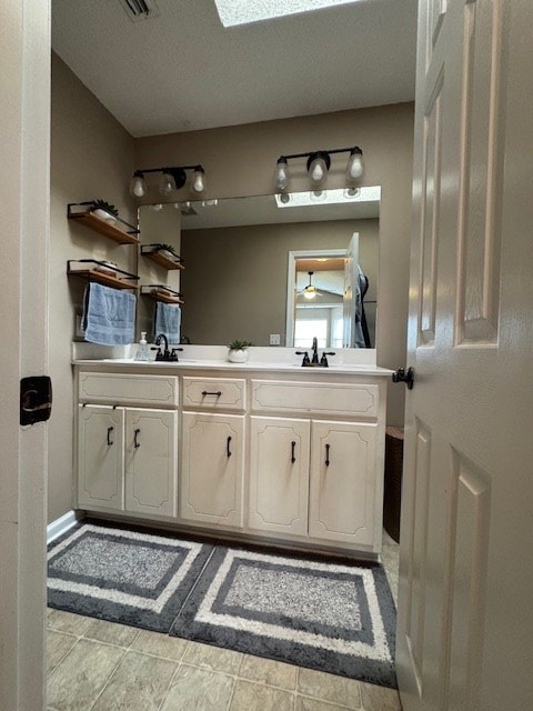 bathroom featuring vanity, ceiling fan, and a skylight