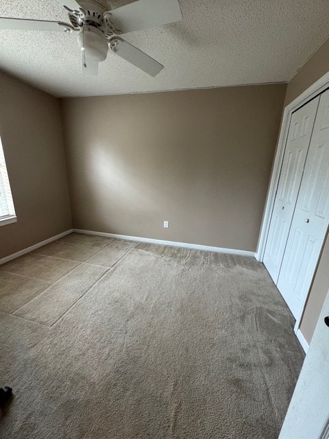 unfurnished bedroom featuring carpet flooring, ceiling fan, a textured ceiling, and a closet