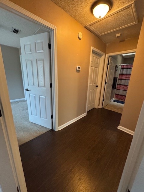 hall featuring a textured ceiling and dark hardwood / wood-style floors