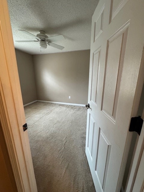 carpeted empty room featuring ceiling fan and a textured ceiling