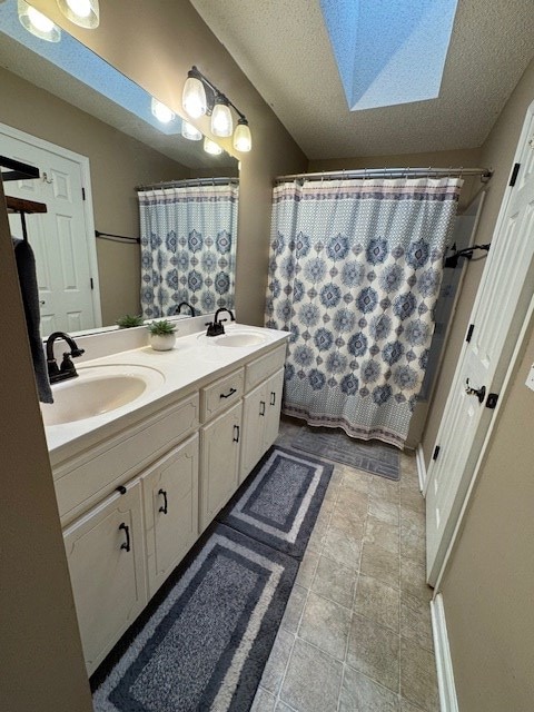 bathroom featuring a skylight, curtained shower, vanity, and a textured ceiling