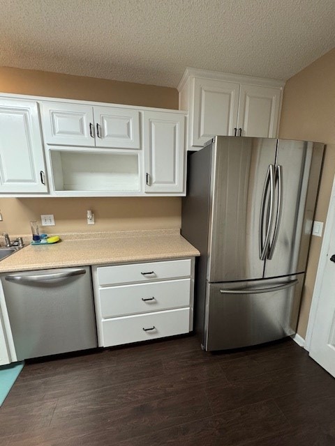 kitchen with white cabinets, appliances with stainless steel finishes, a textured ceiling, and dark hardwood / wood-style flooring