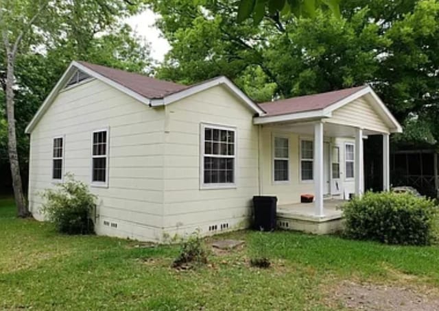 back of property featuring a yard and a porch