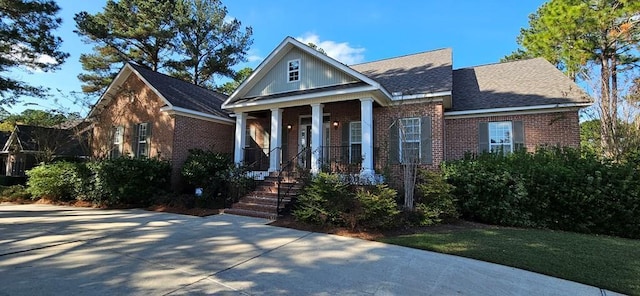 neoclassical / greek revival house featuring covered porch, brick siding, and a shingled roof