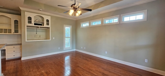 interior space featuring baseboards, a ceiling fan, dark wood finished floors, and crown molding