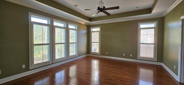 unfurnished room featuring a healthy amount of sunlight, crown molding, a raised ceiling, and hardwood / wood-style flooring