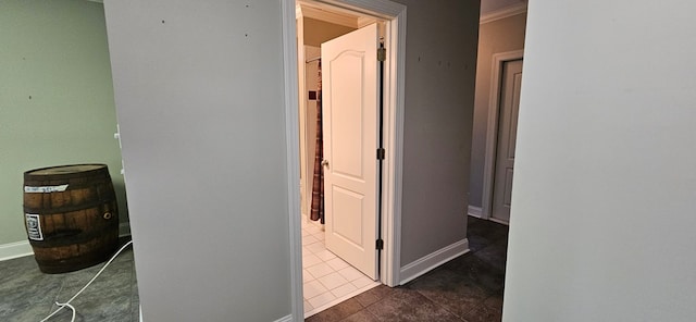 hall featuring baseboards and dark tile patterned flooring