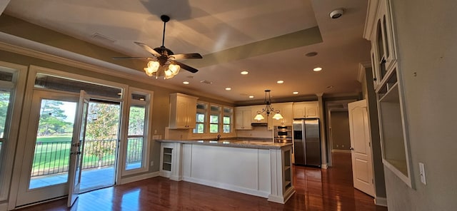 kitchen featuring dark wood-type flooring, ornamental molding, stainless steel fridge, a peninsula, and white cabinets