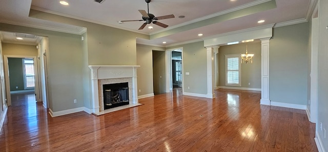 unfurnished living room featuring a wealth of natural light, a fireplace with flush hearth, wood finished floors, and ornate columns