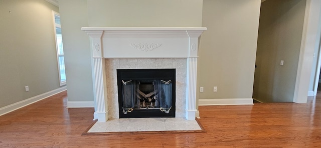 interior details featuring a fireplace with flush hearth, wood finished floors, and baseboards